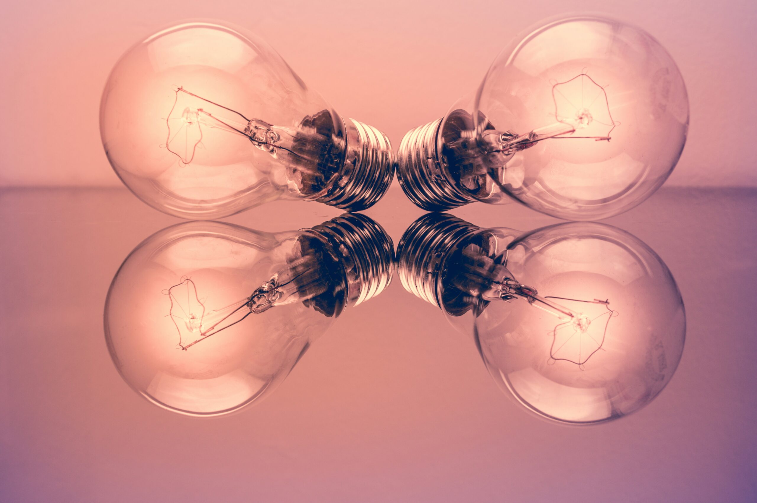 Four light bulbs reflecting on a surface, symbolising creative ideas and inspiration