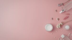 Minimal skincare products and flowers on a soft pink background, representing cosmetics translation for English-speaking markets