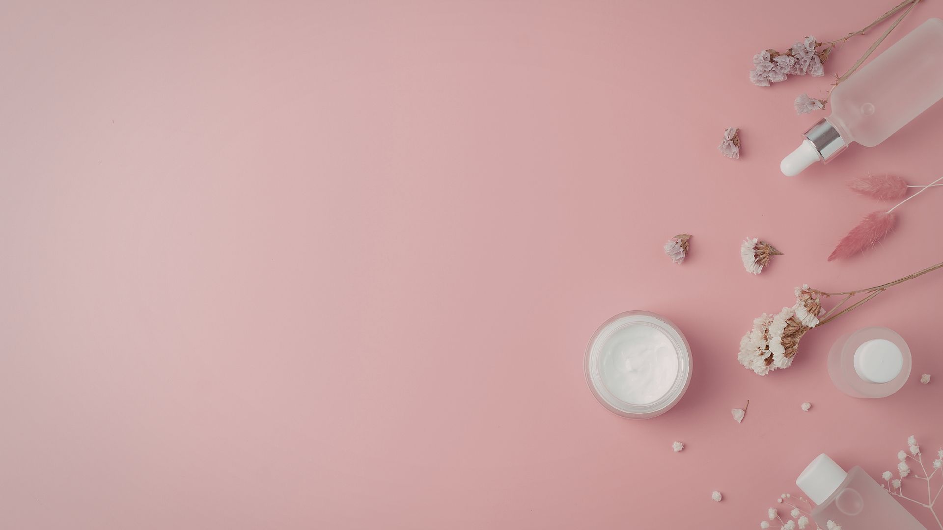 Minimal skincare products and flowers on a soft pink background, representing cosmetics translation for English-speaking markets